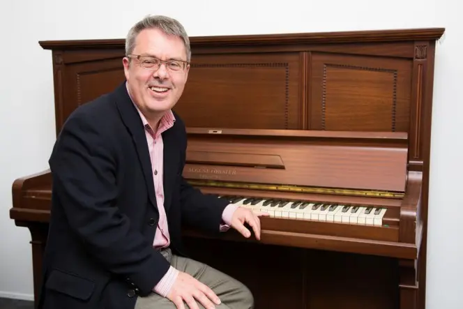 Chris Bourke seated at Douglas Lilburn’s piano.