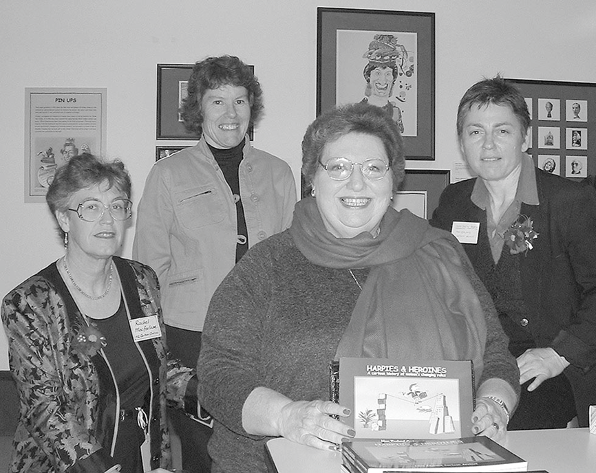 Black and white photo of four women with one holding the newly launched book.