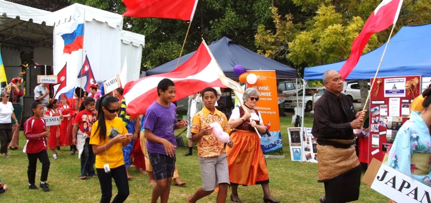 People from Pacific countries holding flags or signs with their country's name parading in a multicultural festival event