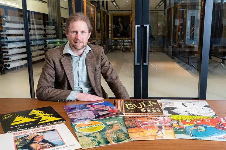 Man sitting at a table with record covers in front of him.