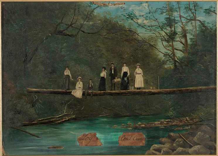 A group of seven men and women on a log bridge. 