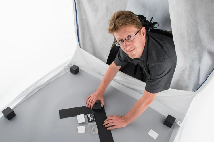 A view of the purple DAT tape preparing to be photographed from further away, includes photographer smiling up at the camera.