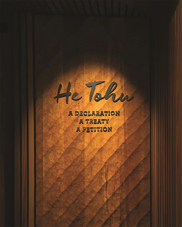 The text 'He Tohu - A Declaration, A Treaty, A Petition' spot lit on a wooden wall.