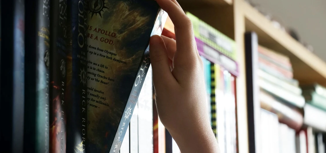 Photo showing a school student's hand selecting a book in a school library.