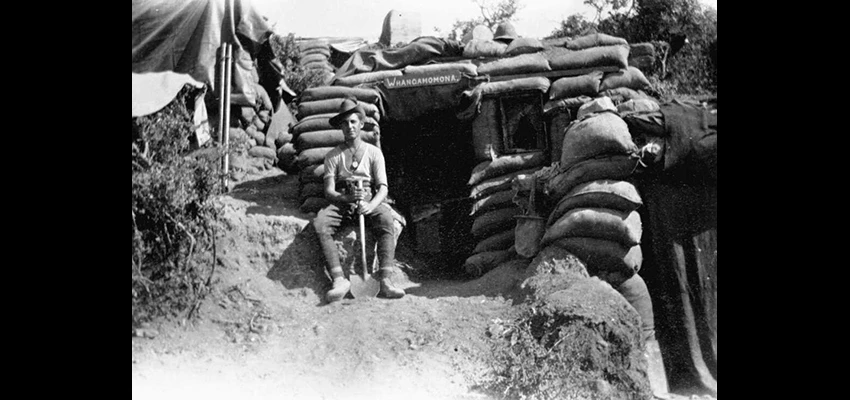 An unidentified New Zealand outside his dug-out in a trench during World War I. A sign above the door reads 'Whangamomona' which may be where the soldier hails from.