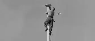 Man fixing a flagpole at the top of the Evening Post building, Wellington, 1956.