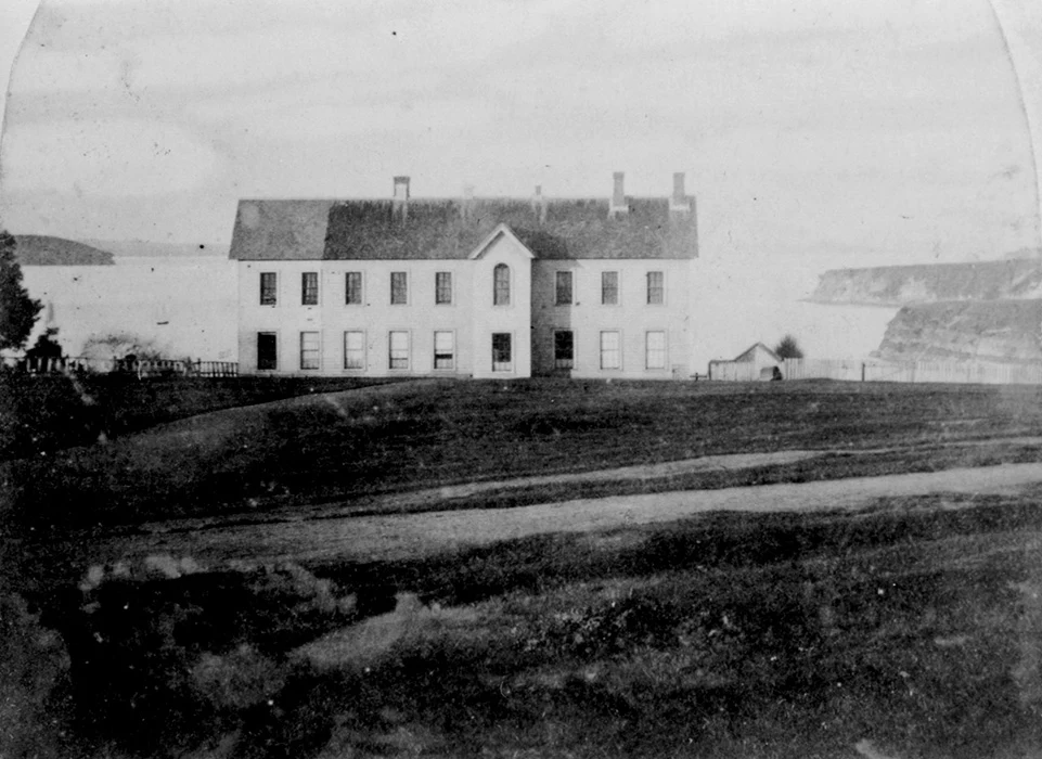 Black and white photograph of NZ's first Parliament building — the Auckland Provincial Council building. The coast can be seen in the background.