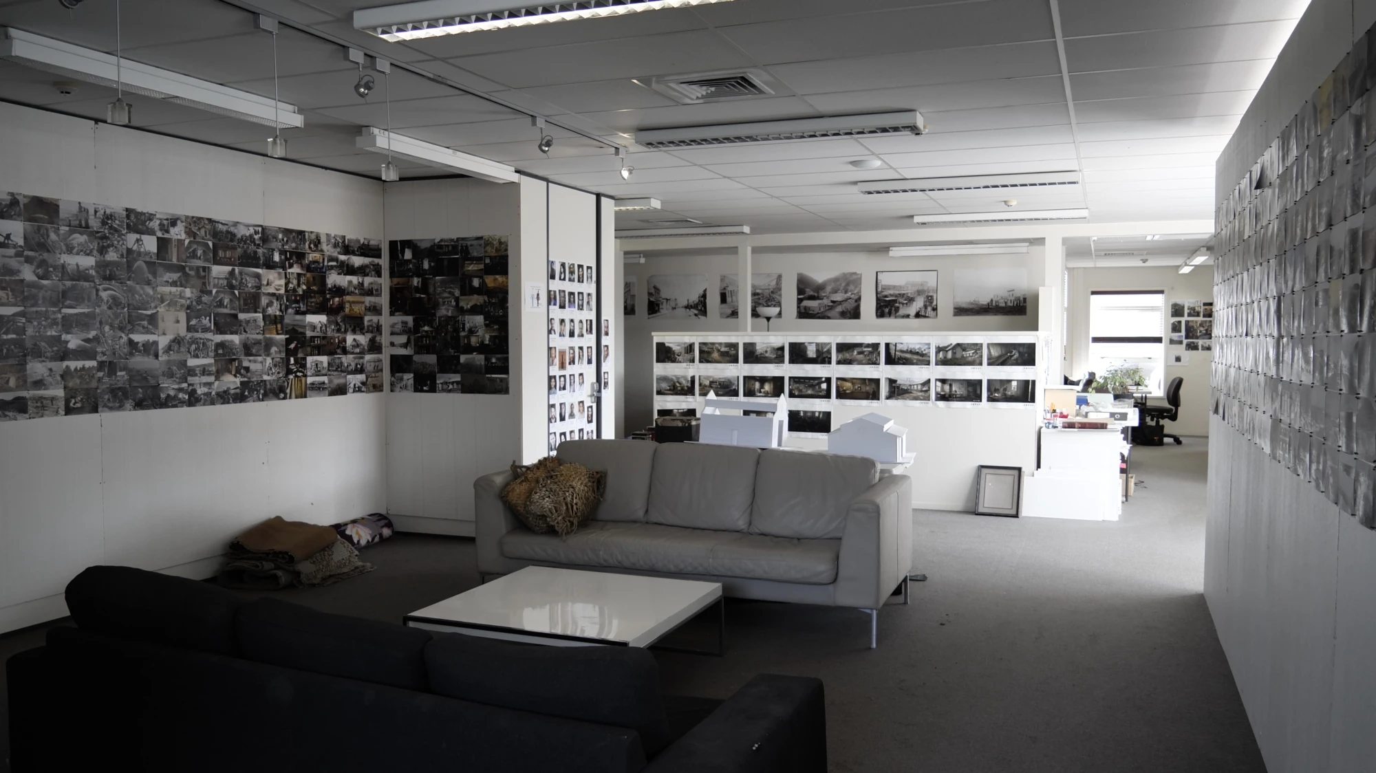 Art department with sofas and low table and walls covered in individual photos neatly arranged in a grid wrapping around the entire space.