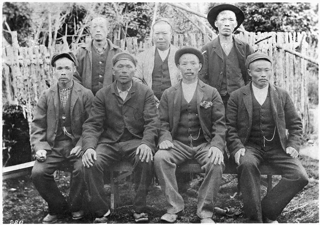 Black and white group, posed photo of Chinese 7 gold seekers in an outdoor setting.