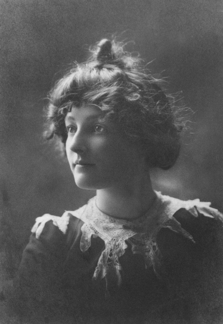 A black and white studio portrait of a woman wearing a lace collar with her hair pulled up.