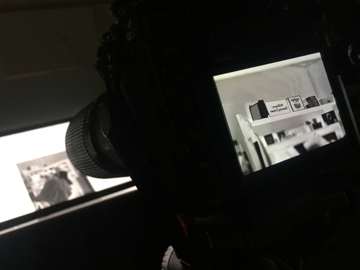 A darkly lit photo seen from behind the camera showing the camera preview screen and photographer's work flow and process.
