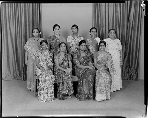 Group studio photo of seven Indian women wearing saris.