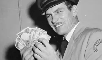 Magician John Calvert looks at some money, 1950.