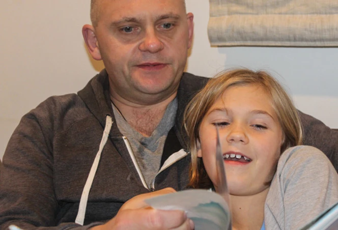 Dad and girl reading together.