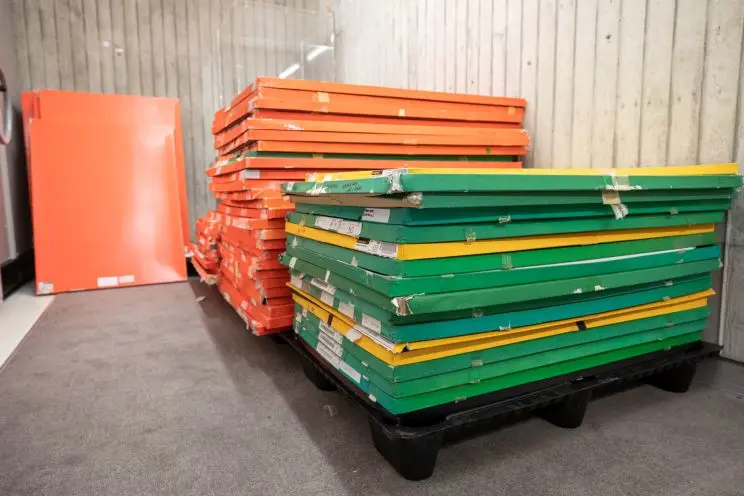 Two stacks of large, flat orange and green boxes containing architectural drawings and prints. 