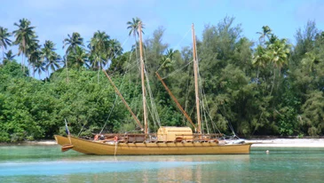 Large traditional double-hulled vaka in Rarotonga moored with sails let down