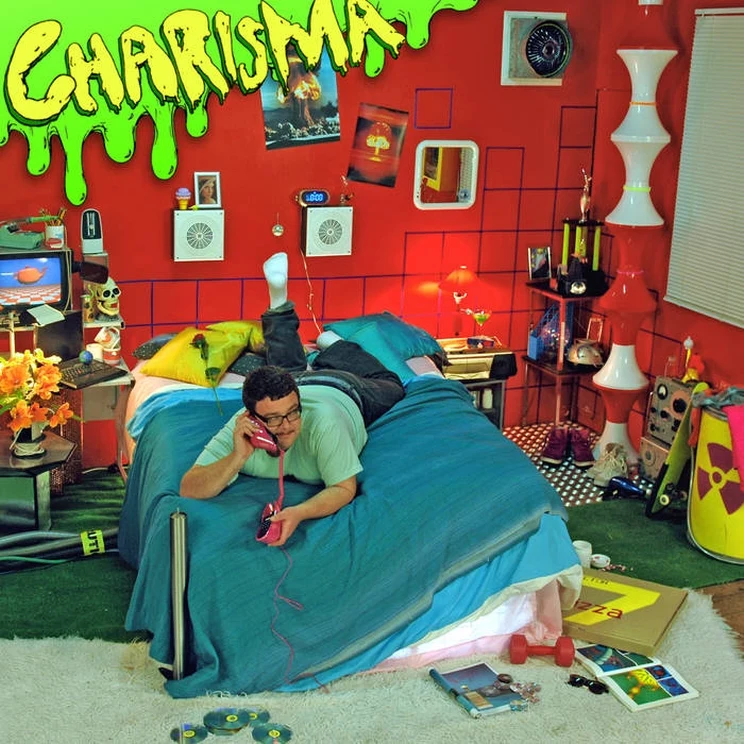 An album cover using bright neon colours depicting a teenager on his bed talking on a corded phone in a bedroom decorated in an re-imagined 1990s style.