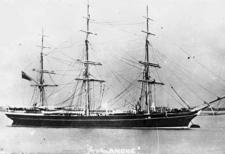 Black and white photo of a three-masted sailing ship at anchor.