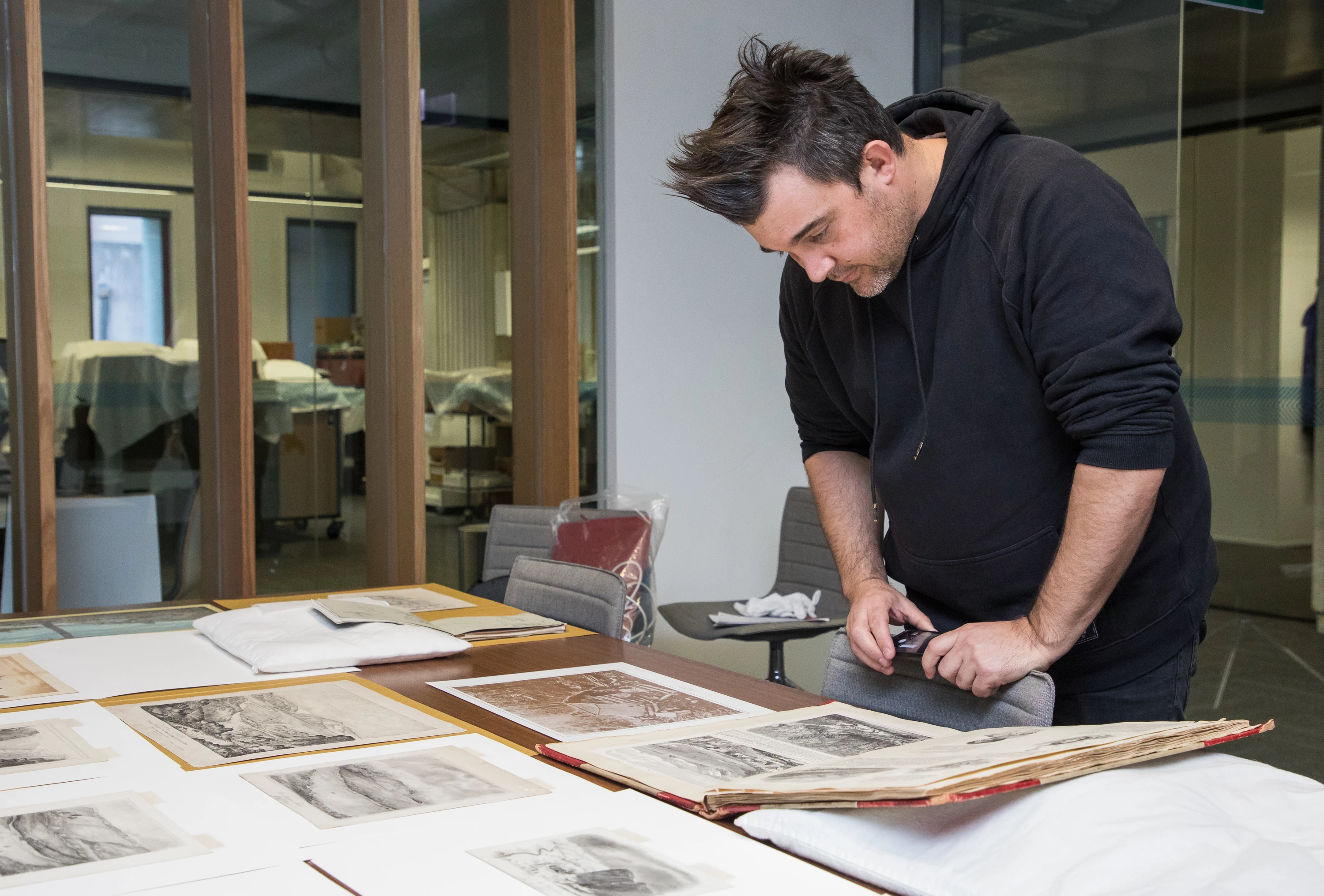 Daniel Birt looks at collection images that have been spread out onto a table. 