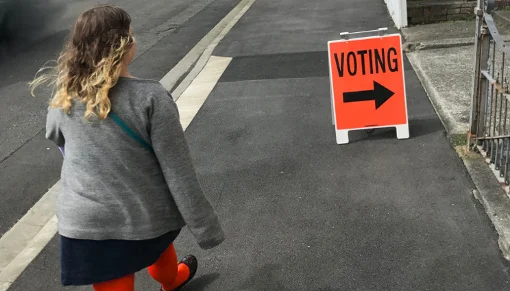 Woman walking purposefully towards voting sign