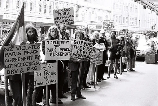 A group of people standing in the street holding signs in support of the Paris peace agreement.