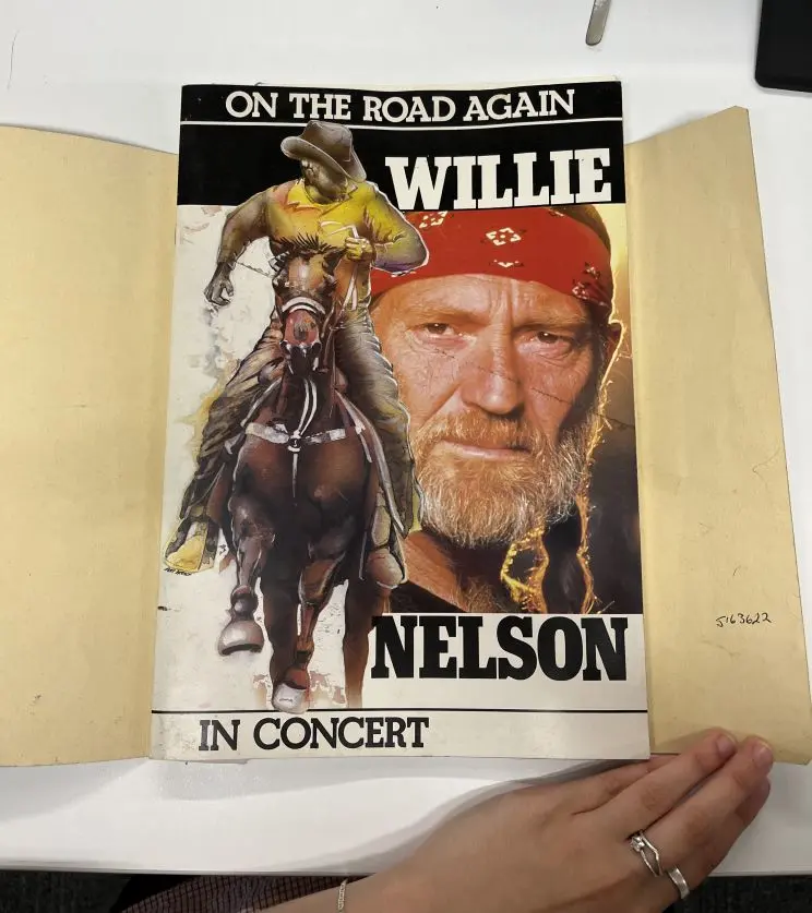 An open folder shows an A3-sized picture of a concert flyer with the words, "On the road again. Willie Nelson in concert" and a portrait of Mr Nelson along with a man riding a horse.