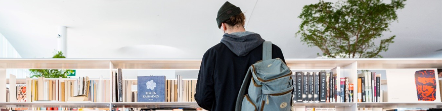 A man looking at bookshelves in the library.