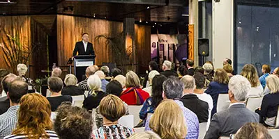 People seated at an event listening to a speaker. 