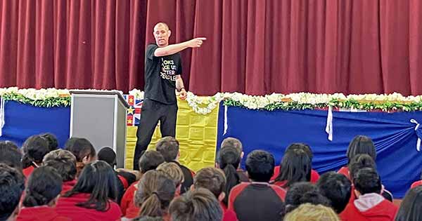 Te Awhi Rito Reading Ambassador Alan Dingley speaking on stage to a group of students.
