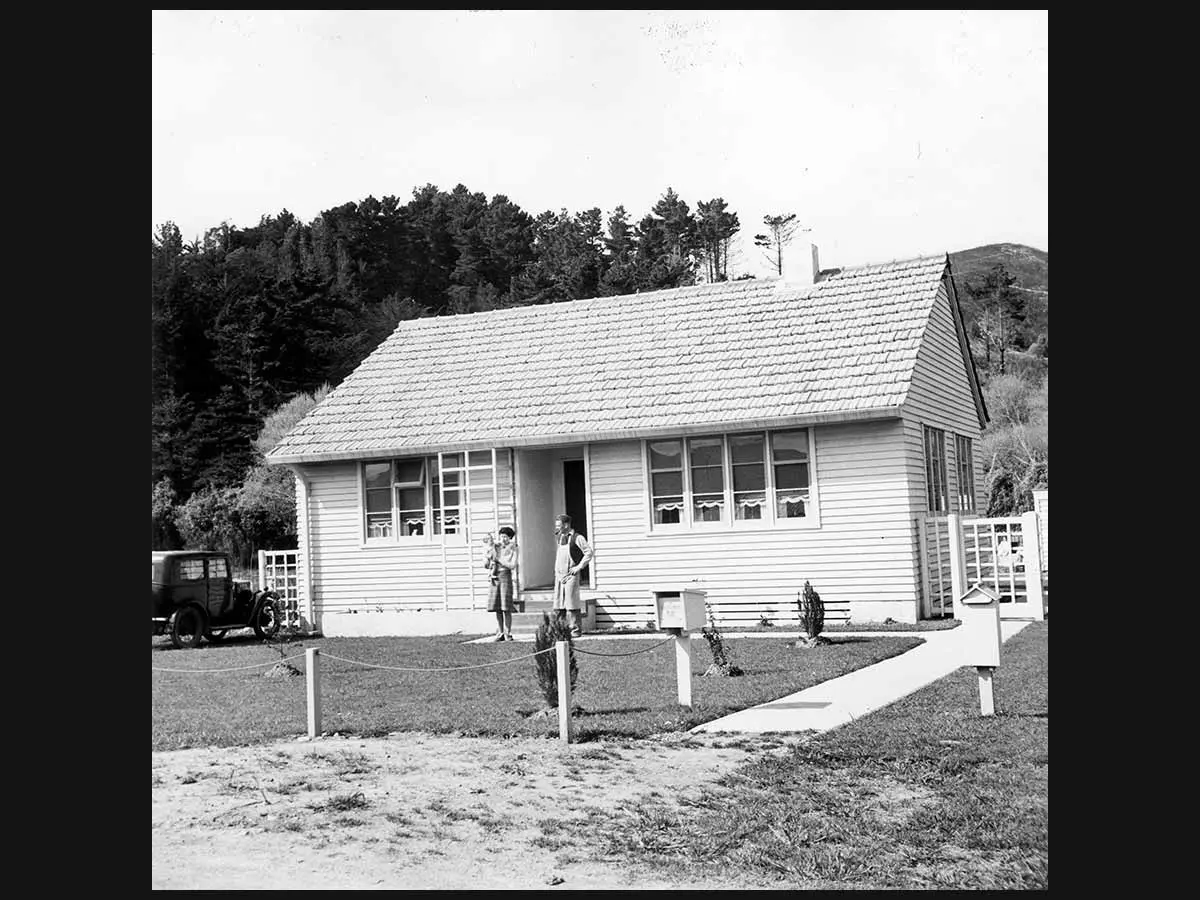 The Holmes family standing outside their state house in Lower Hutt. A car is parked in the driveway on the left.