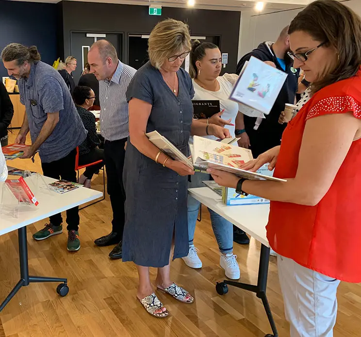 Adults picking up and reading books. 