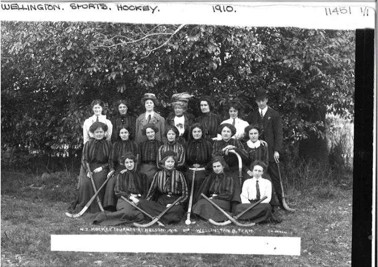 A black and white group portrait of a women's field hockey team from 1910 shown holding their sticks.