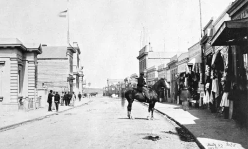 Street scene with pedestrians and a man on a horse.