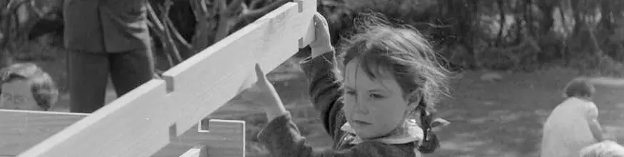 Girl in playground building a wooden structure.