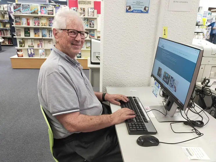 Older man sitting at a desk with a computer on it.