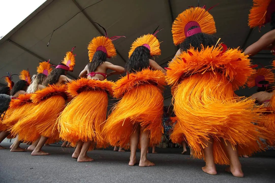 Colour photo of Pacific students performing the ura pau (drum dance) at ASB Polyfest. They are wearing a headpiece, kiriau skirts and titi on their hips.