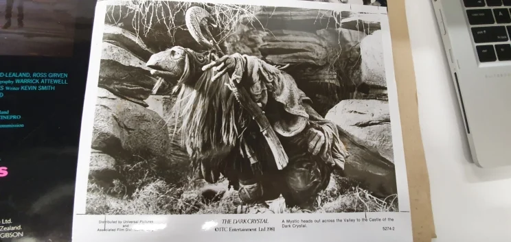 A black and white photo of a puppet in elaborate costume and holding a staff.