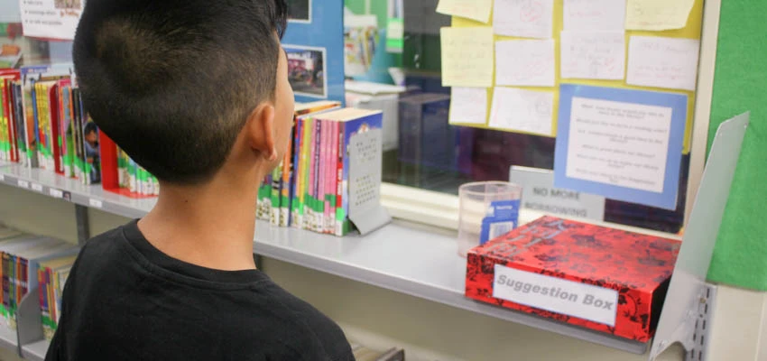 Student in library looking at 'suggestion box'.