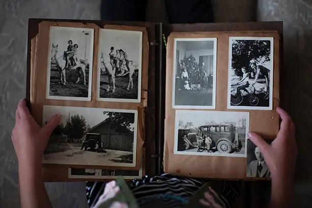 Colour photograph of a child holding a photo album open showing pages of black and white family photographs.