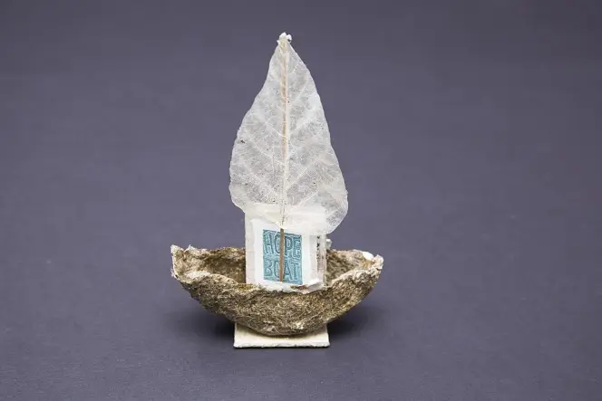 Tiny intricate book called 'Hope Boat', presented within a shell boat, with a leaf for a sail.