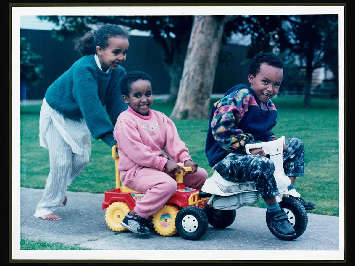 Refugee children from Somalia in East Africa. 3 children are playing outside with a toy car and motorbike. From left to right: Isir Yusef, Bilan Yusef and Mohamed Ali Yusef.