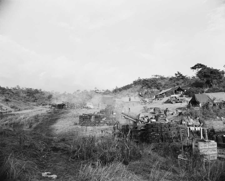 Two large gun emplacements and camp life with jeeps and men drying clothing and making preparations.