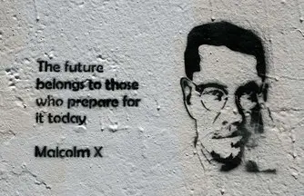 Malcolm X Stencil. There is a stenciled picture of Malcom X beside writing that says 'The future belongs to those who prepare for it today. Malcom X'.