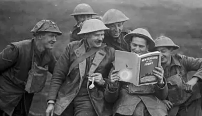 Soldiers crowding around to look at a book. 