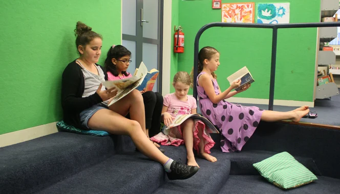 Children reading during a class session at a school library.