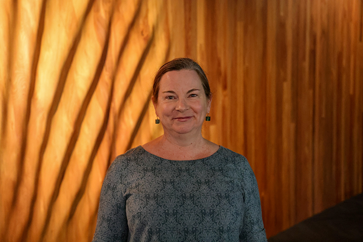 Smiling woman in front of a beautifully carved wooden wall. 