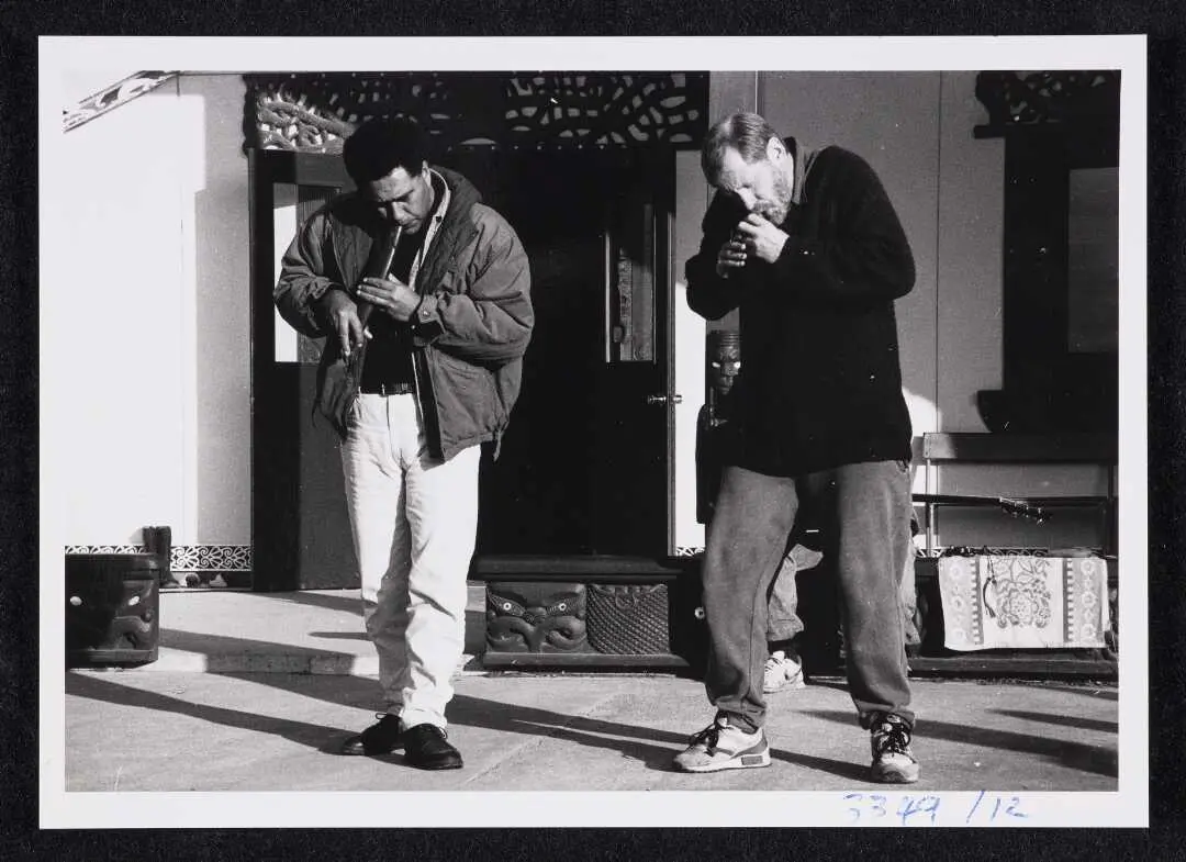 Two men moving rhythmically will they play wind instruments.