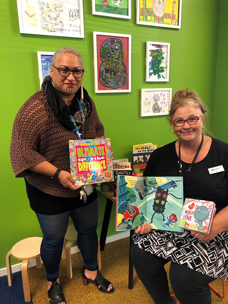 A smiling Māori and Pākehā woman holding books.