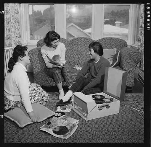 Three Asian women listening to records on a record player.