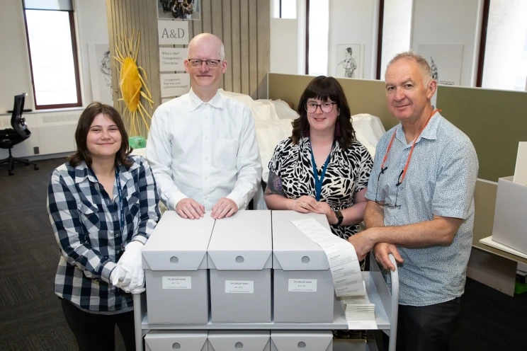 The project team standing behind a cart loaded with grey, archival boxes with labels holding the photographic prints.
